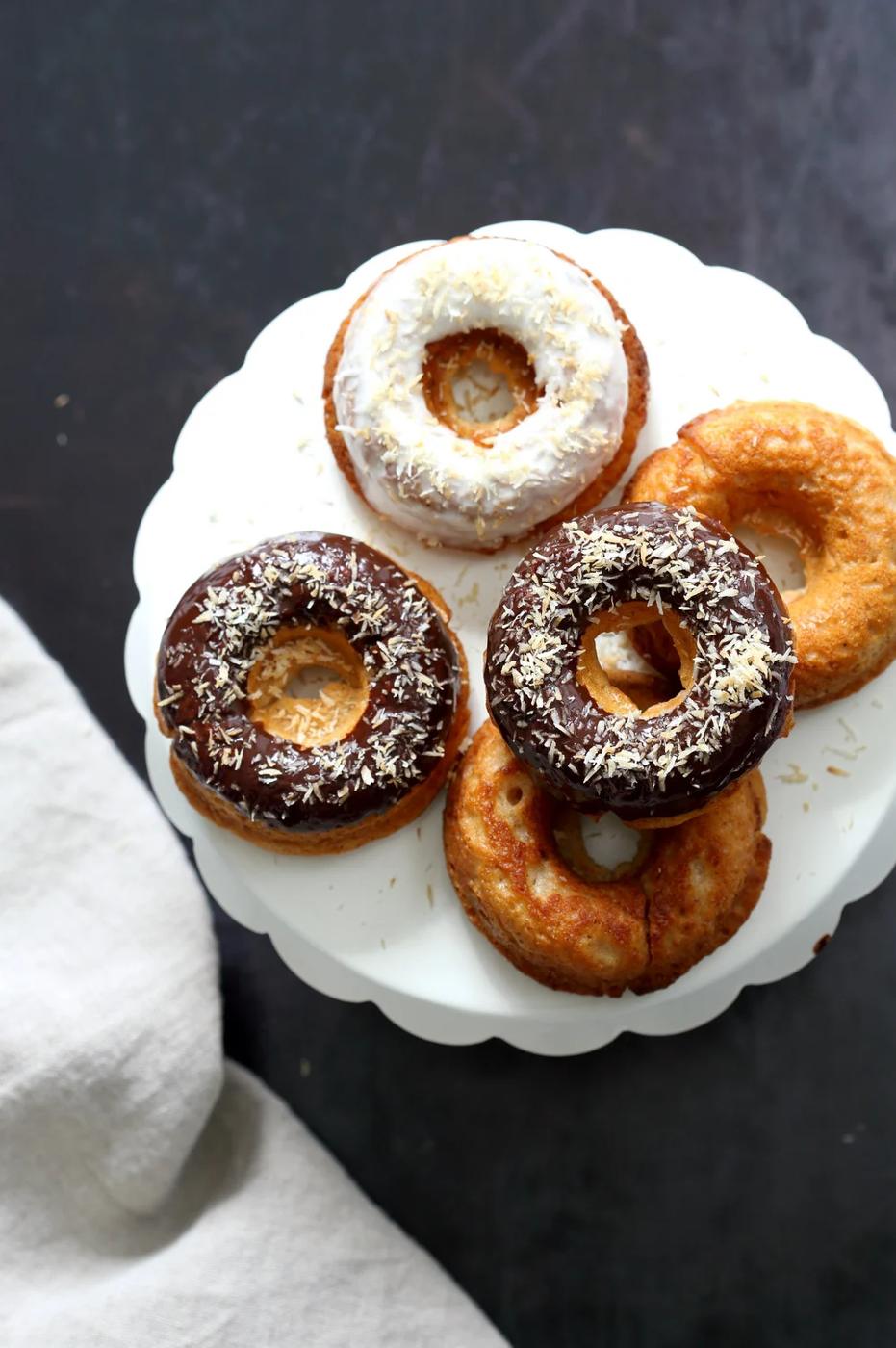 Vegan Banana Donuts with vanilla and chocolate icing on white cake stand