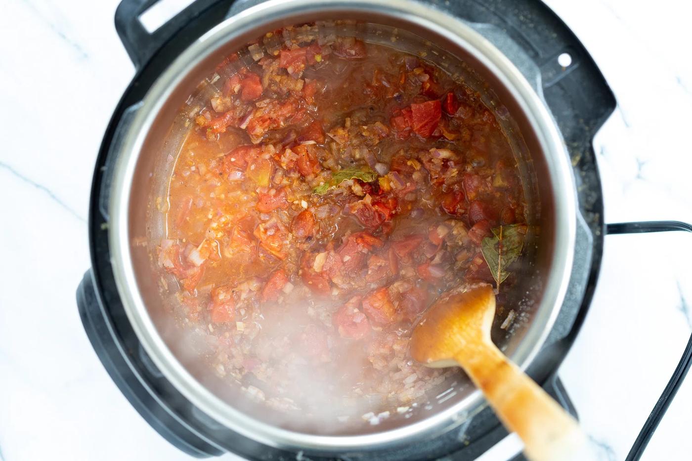 onion, garlic, spices and tomatoes simmering in an Instant Pot
