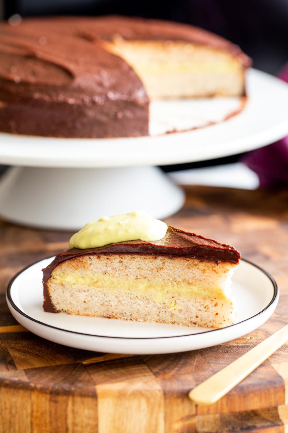 a slice of vegan boston cream cake with a cake in the background