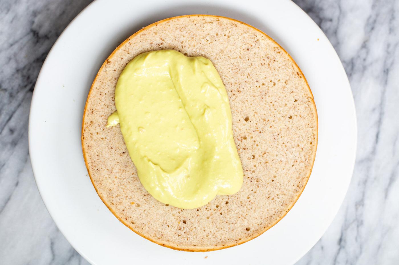vegan custard being spread on a cake layer