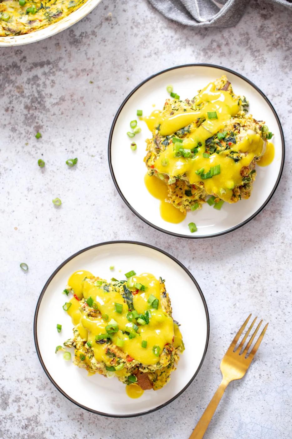 overhead shot of two servings of vegan egg breakfast casserole with vegan hollandaise