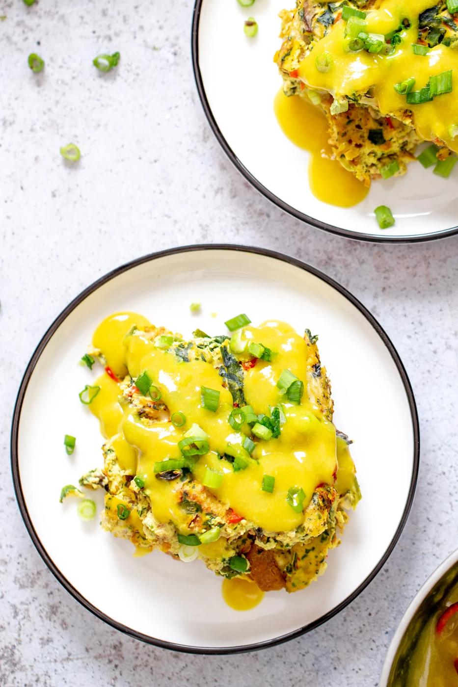 two servings of vegan egg casserole drizzled with vegan hollandaise sauce
