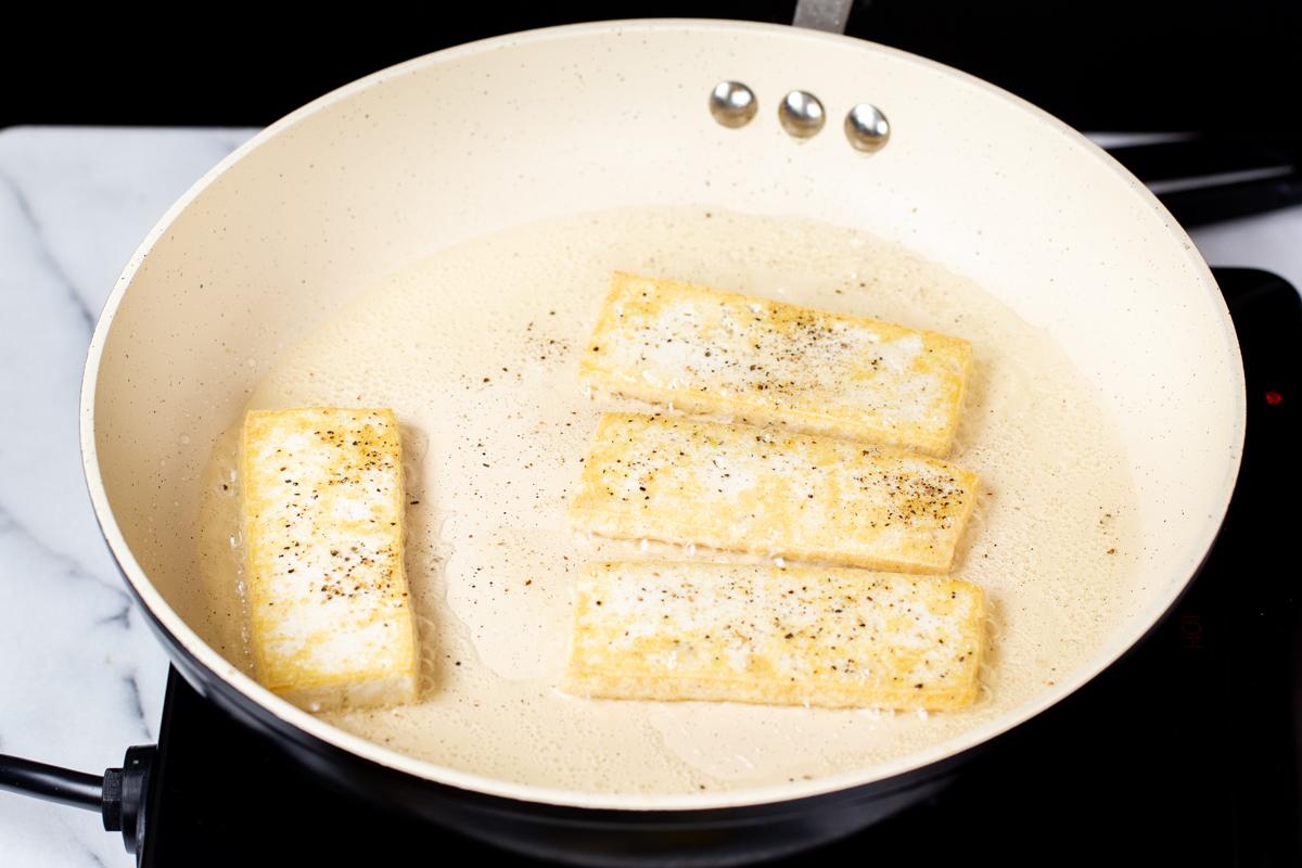 pan-fried sliced of tofu in a sauteeing pan