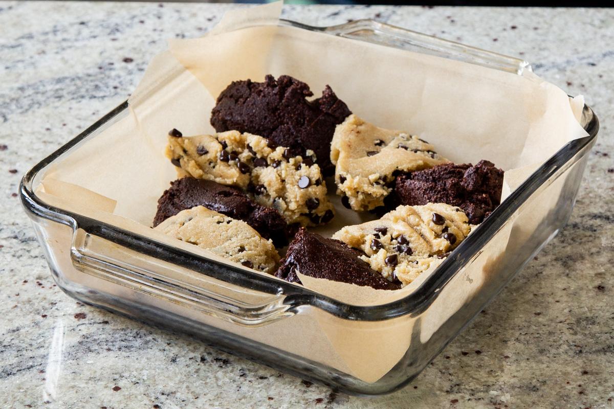 pieces of brownie batter and chocolate chip cookie dough in the lined baking pan