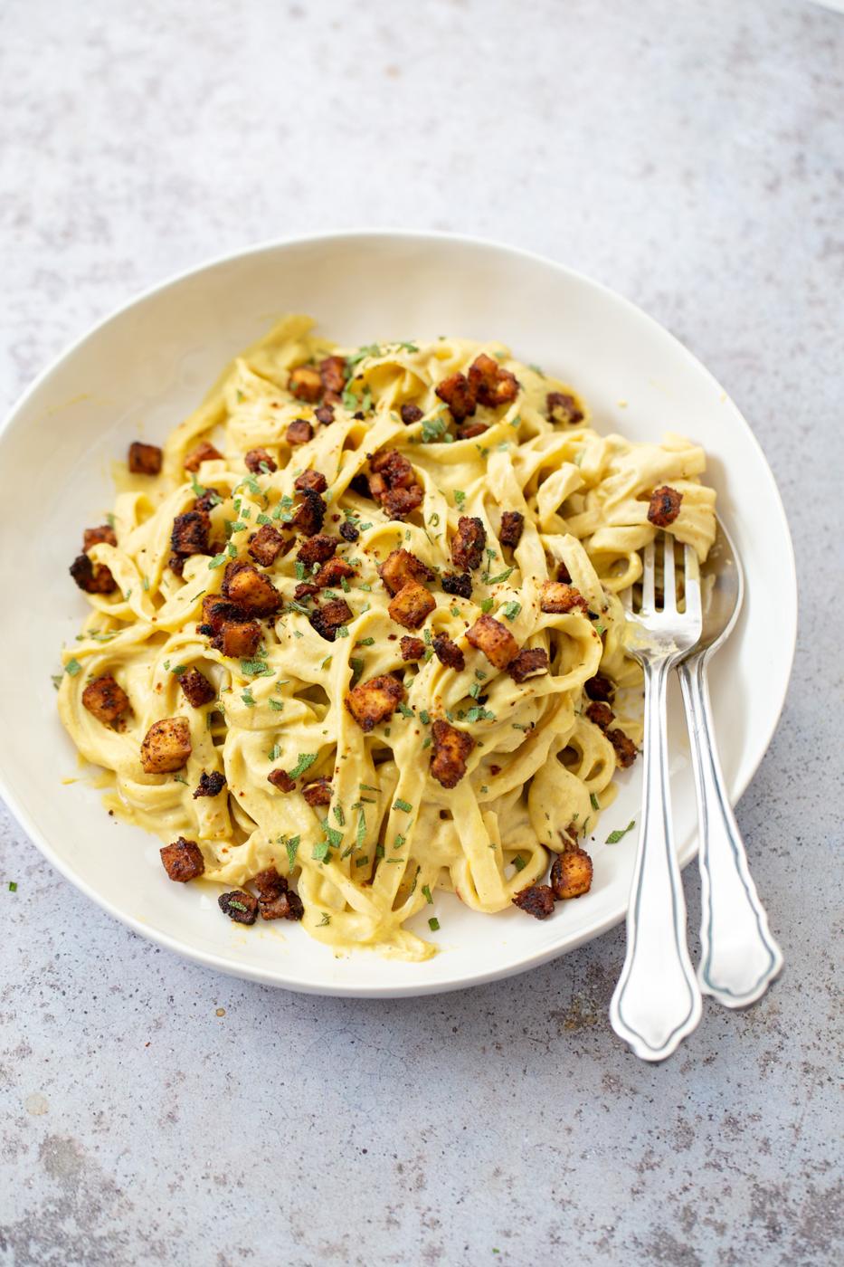 close up of a plate of vegan butternut squash pasta carbonara served with baked tofu