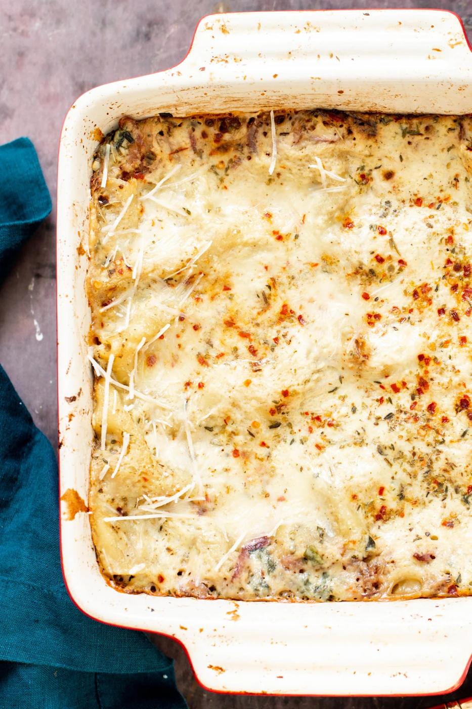 a casserole dish with vegan butternut squash lasagna topped with red pepper flakes