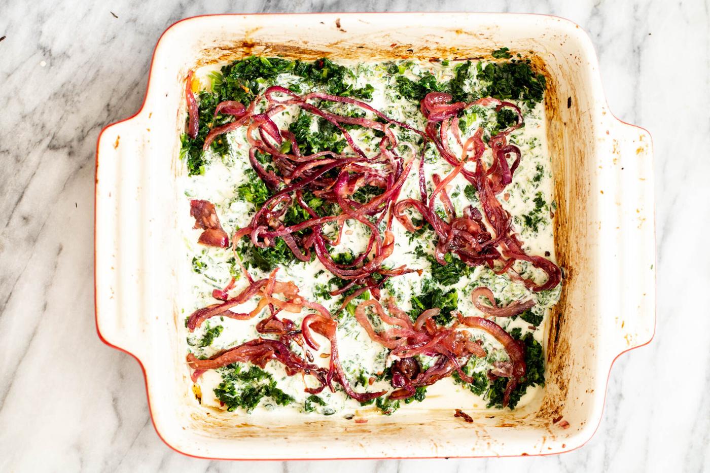 caramelized onion being added on top of spinach and bechamel