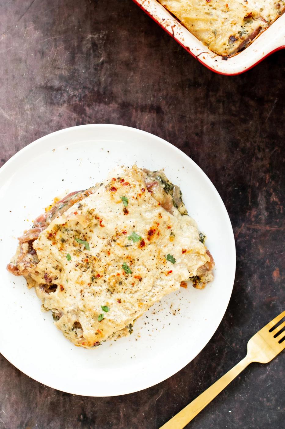 a serving of vegan butternut squash lasagna with spinach on a white plate