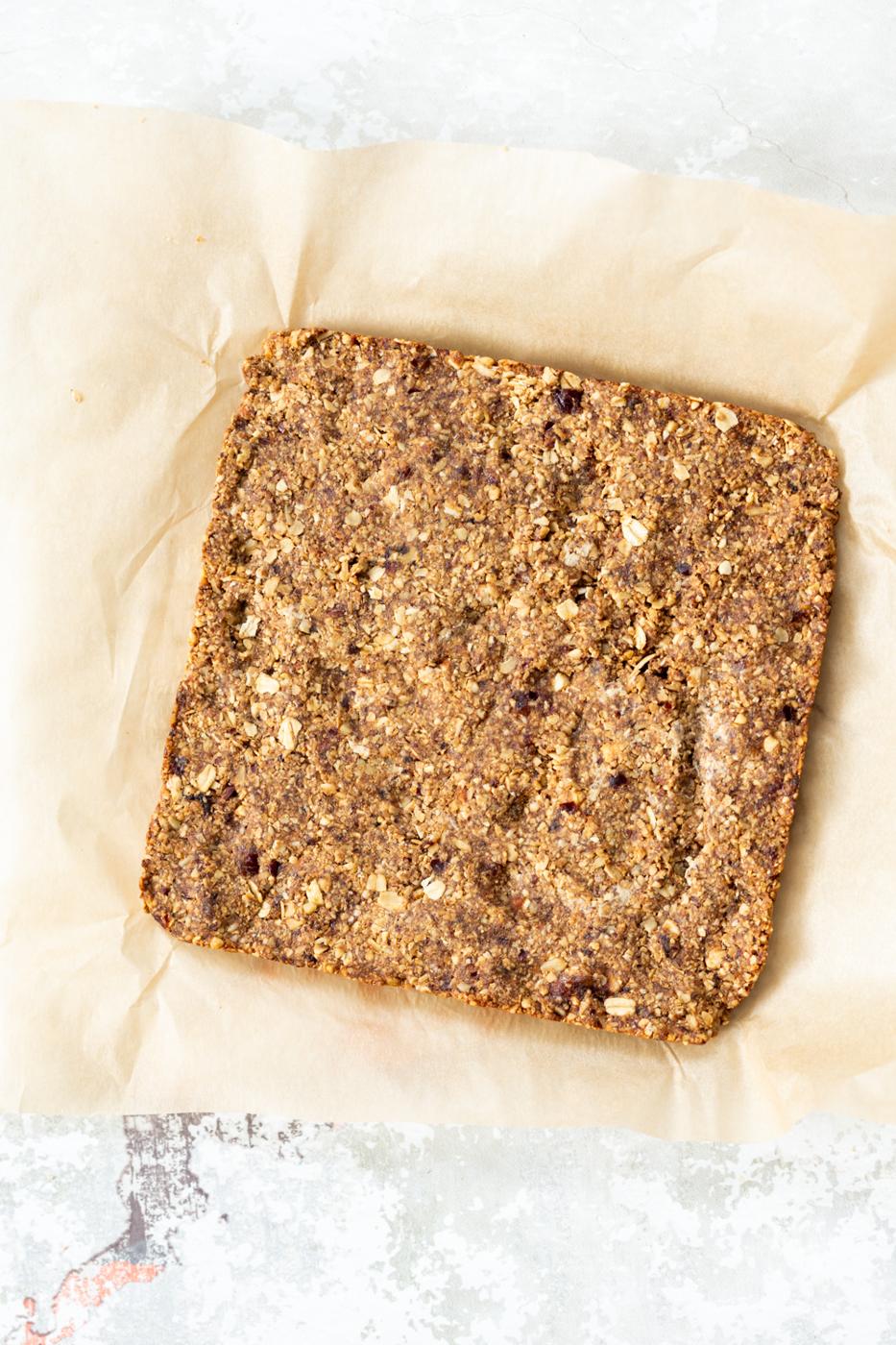 overhead shot of vegan banana granola bars on a sheet of baking paper ready to be cut