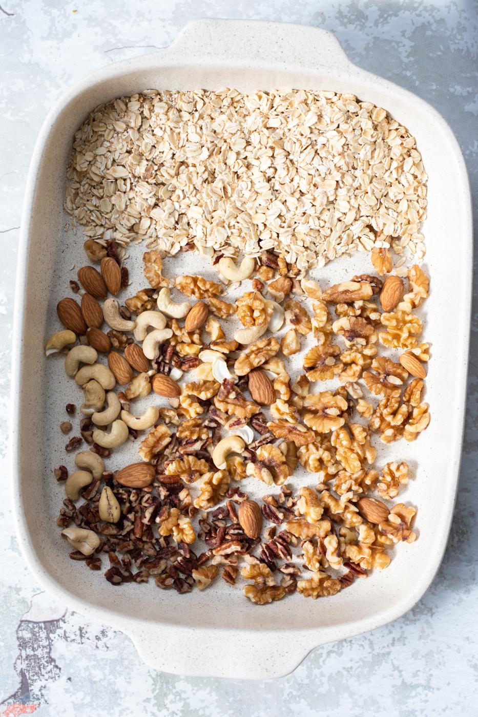 overhead shot of a white casserole dish with ingredients for making vegan banana granola bars