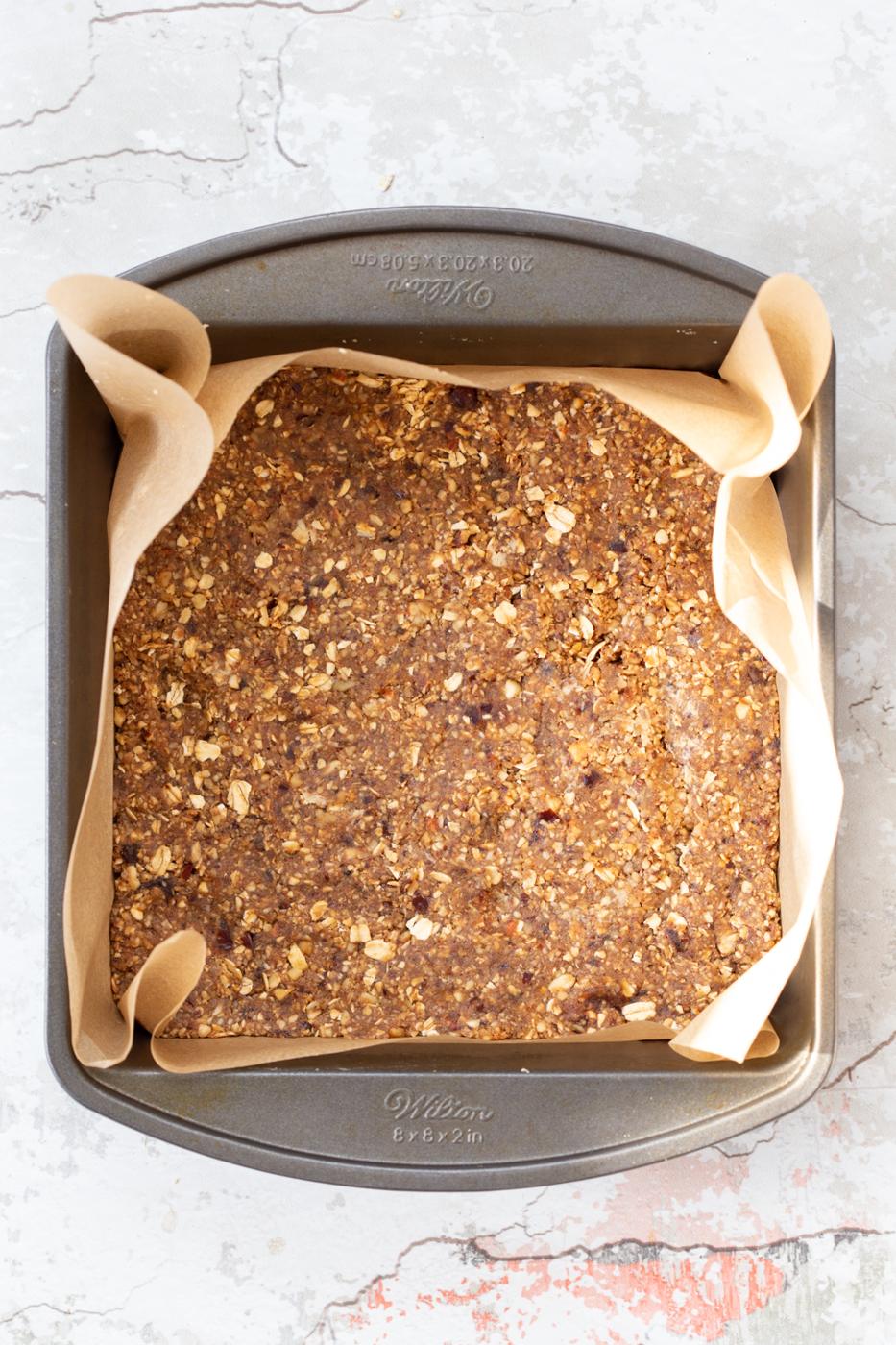 overhead shot of unbaked vegan banana granola bars in a metal baking pan