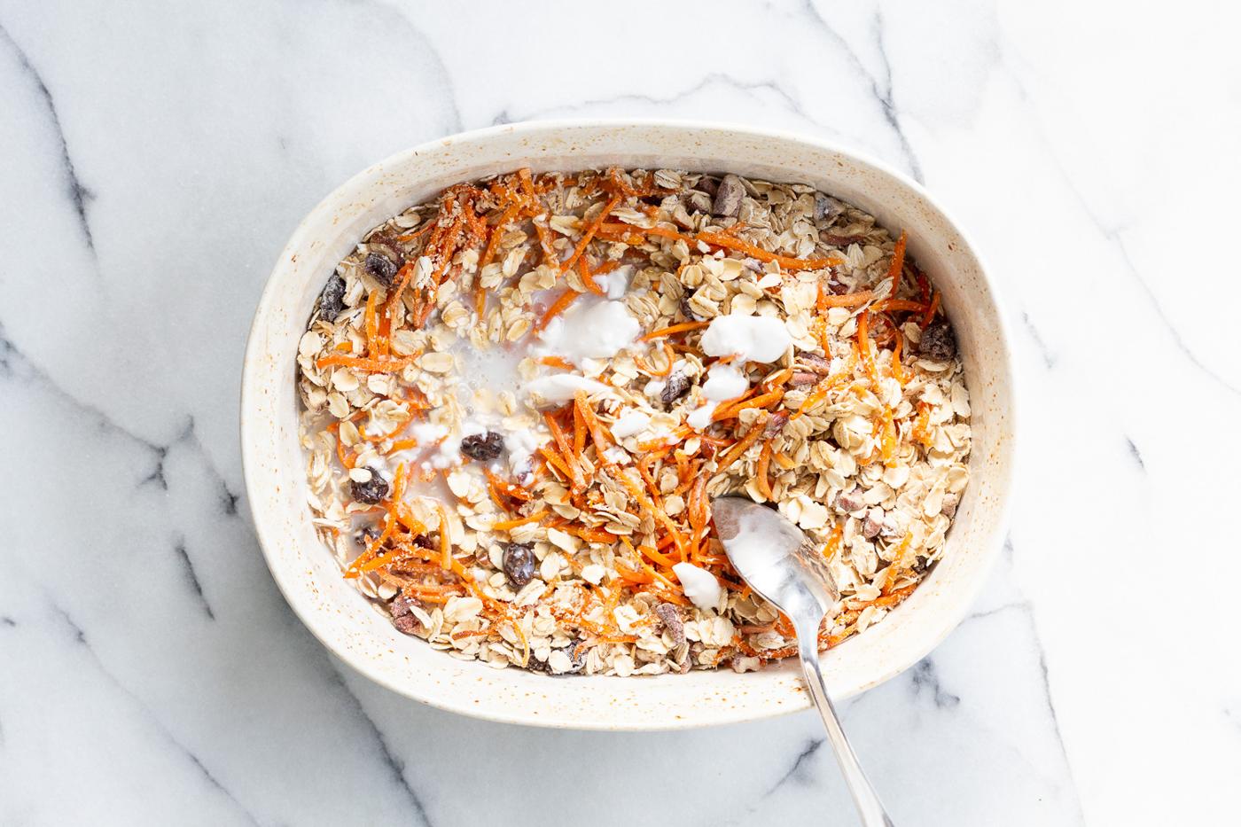 Non Dairy milk mixed with dry ingredients for Our Vegan Carrot Cake Baked Oatmeal in a baking dish