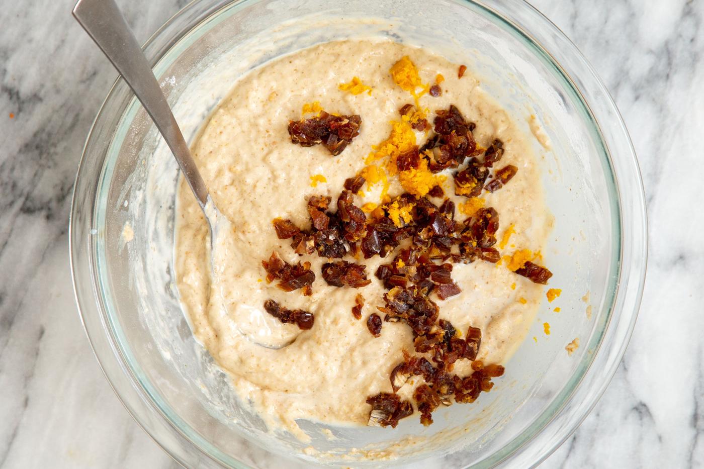 chopped dates and orange zest being added to carrot cake batter