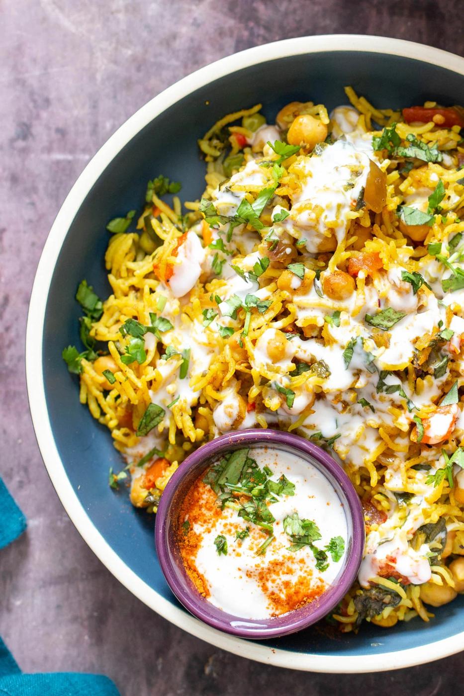 a bowl of baked vegan chickpea pulao drizzled with raita
