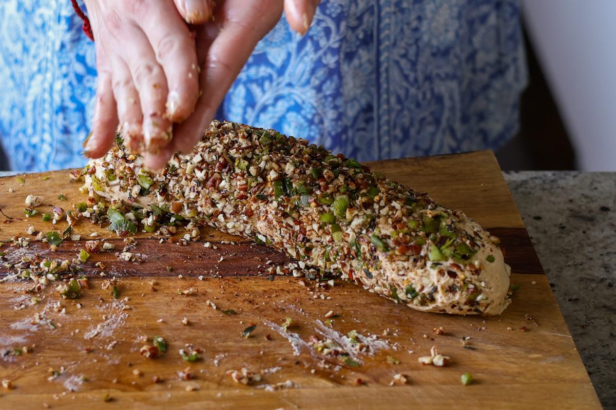 rolling holiday cheese log in the toppings