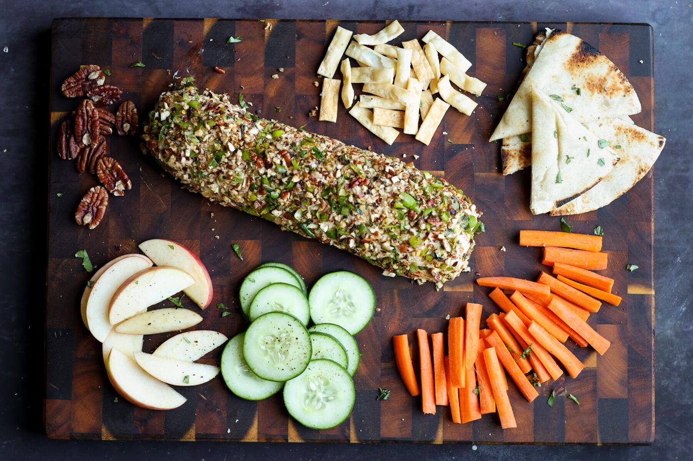 holiday cheese log on a party platter with veggies, chips, pita, and apple slices