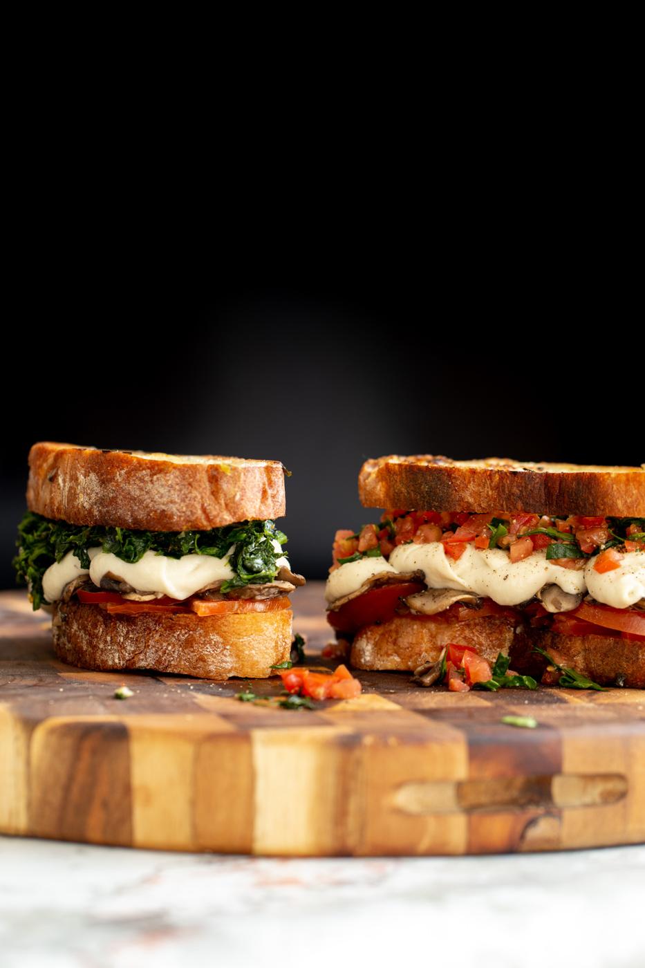 two homemade vegan mozzarella cheese melts with spinach and mushrooms on a wooden board