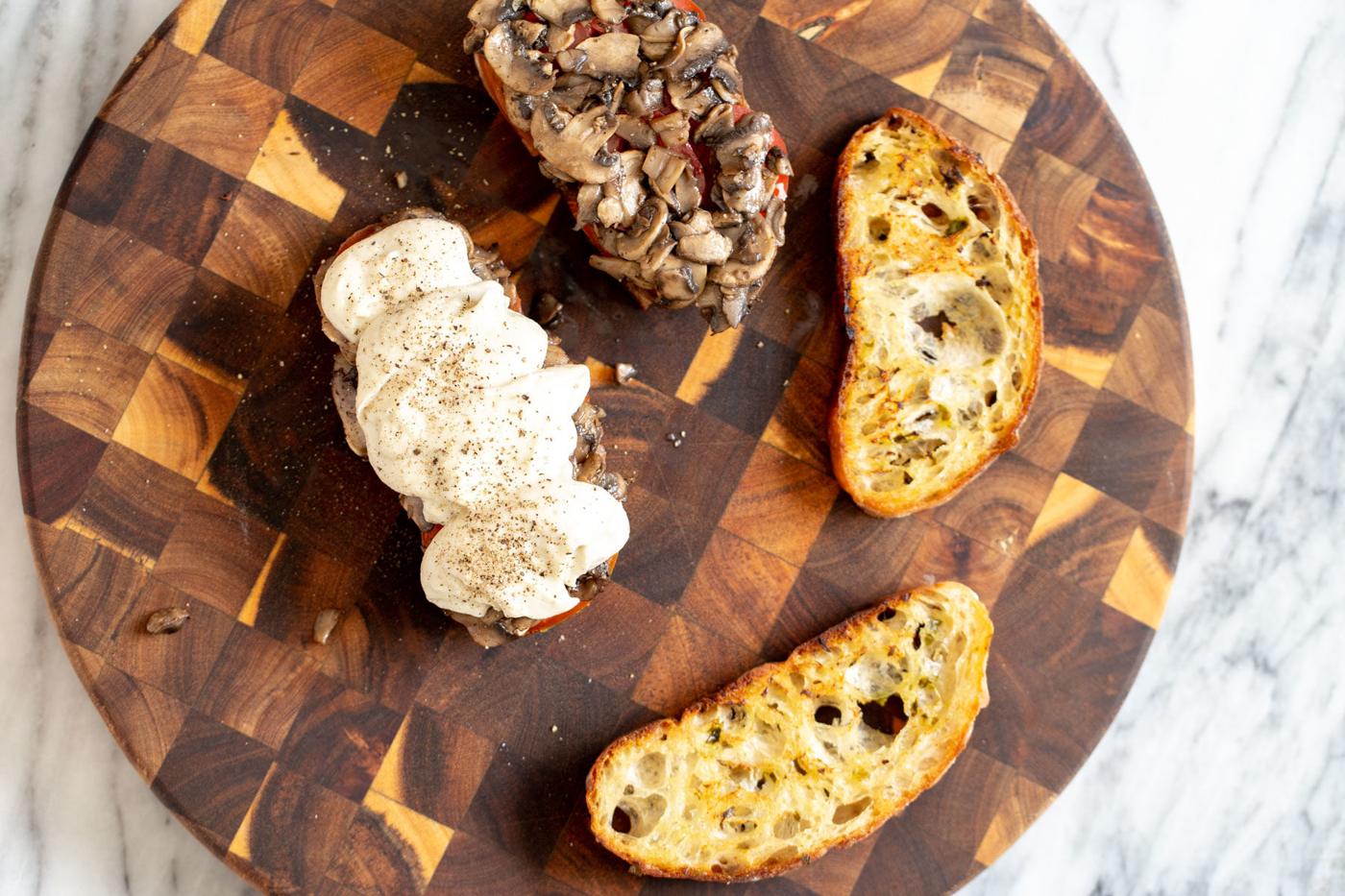 bread sliced being topped with sauteed mushrooms and vegan mozarella cheese
