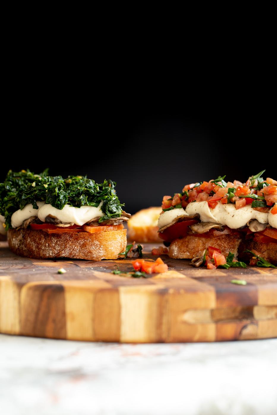 side view of vegan cheese melts topped with spinach and chopped tomatoes