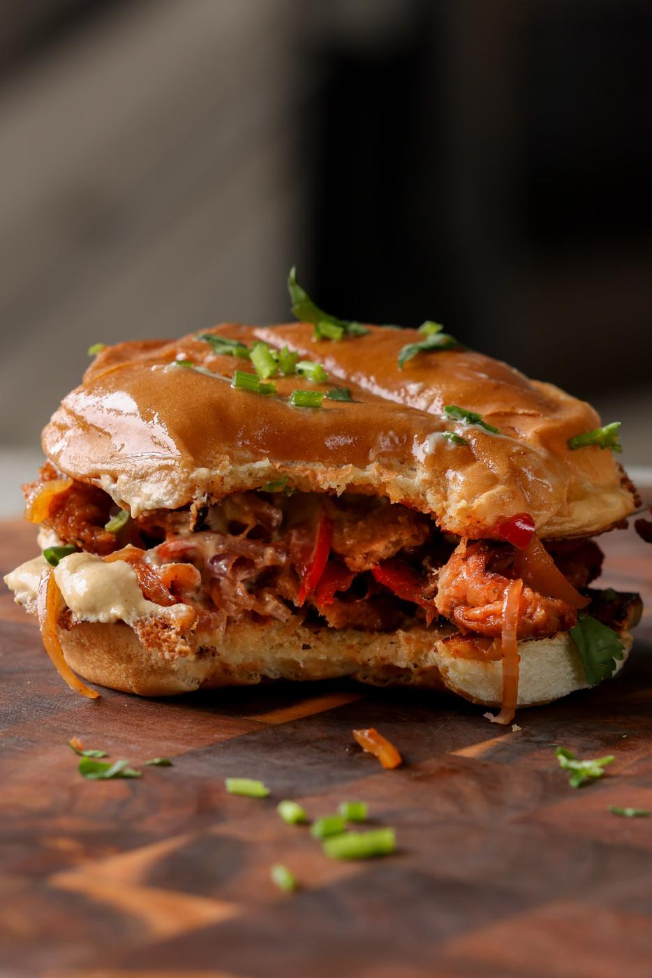 vegan cheesesteak sandwich on a cutting board with a bite taken out