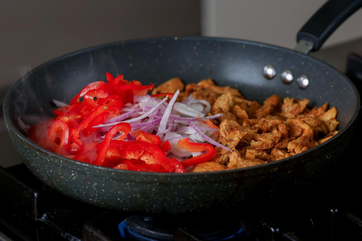 adding onion and pepper to the pan of soy curls