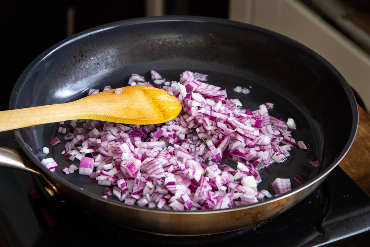 diced onion in a black sauteeing pan
