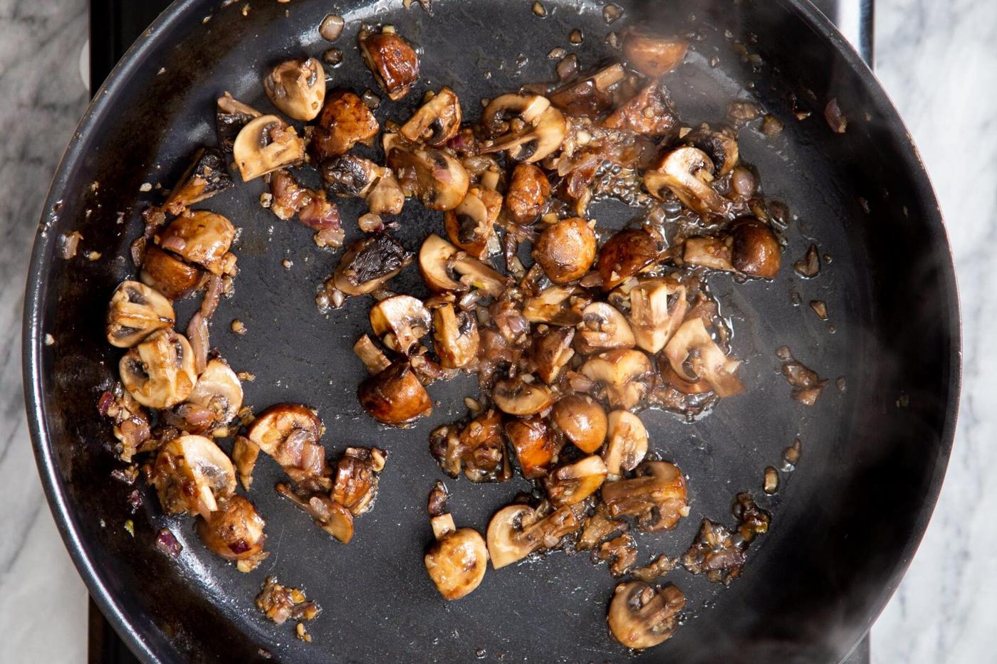 golden fried muhsrooms with garlic and onion in a skillet