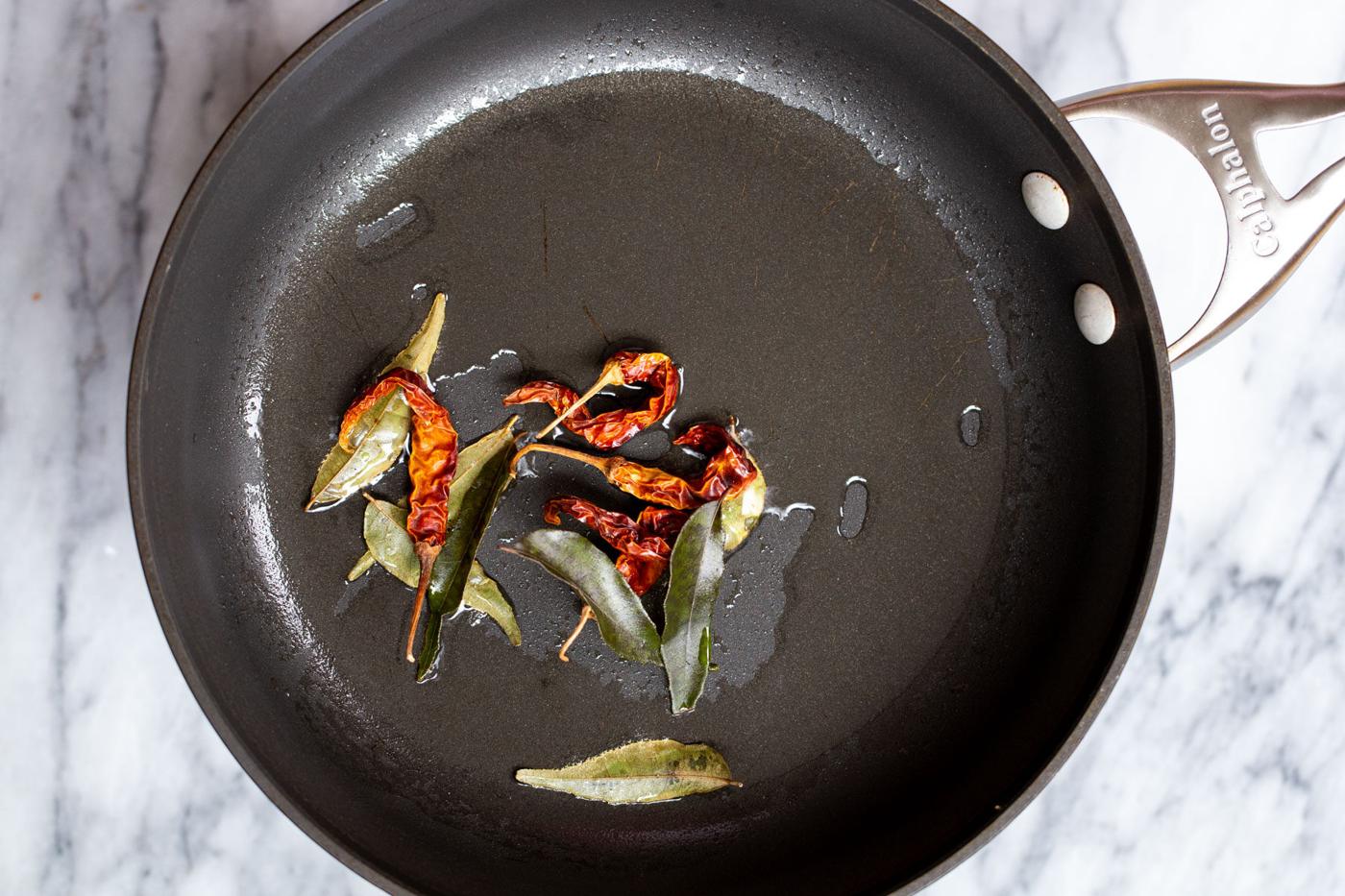 chilies and curry leaves in a black skillet