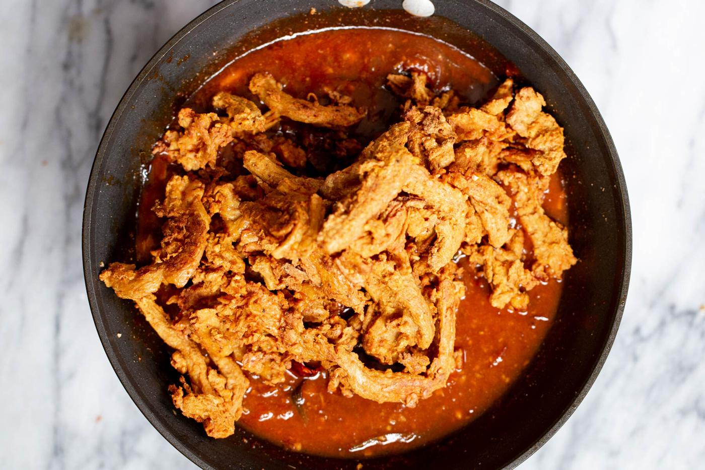 soycurls being added to chili gravy for making vegan chicken kondattam
