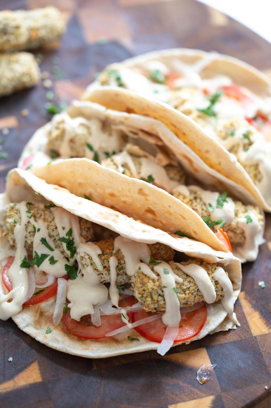 three vegan wraps filled with vegan chickpea quinoa croquettes and drizzled with tahini sauce