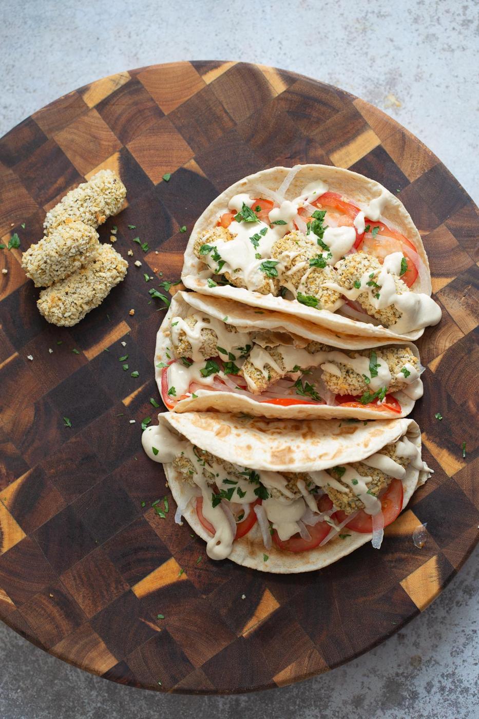 three wraps filled with vegan chickpea quinoa croquettes on a chopping board