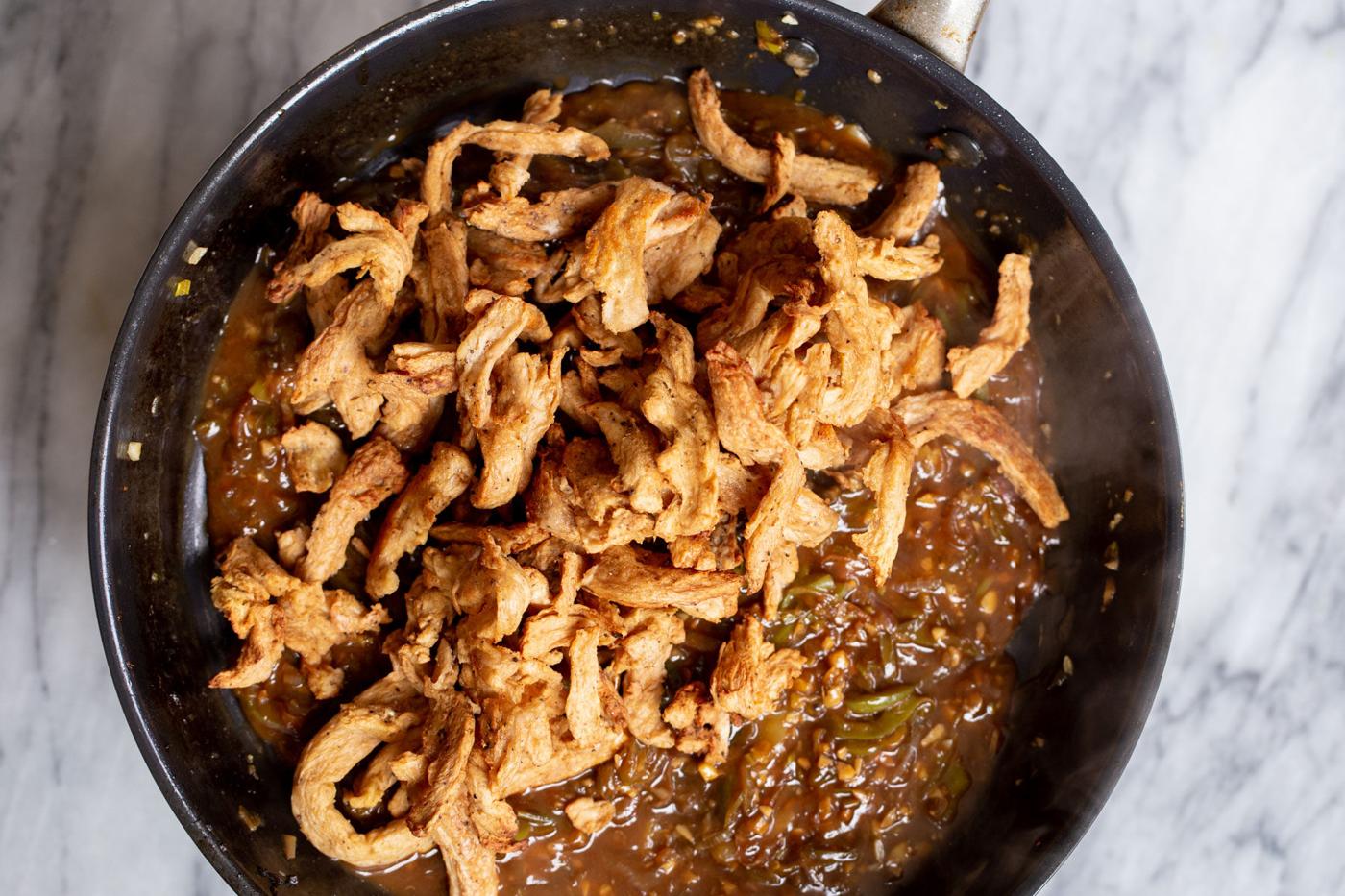 soy curls being added to skillet with chilli sauce