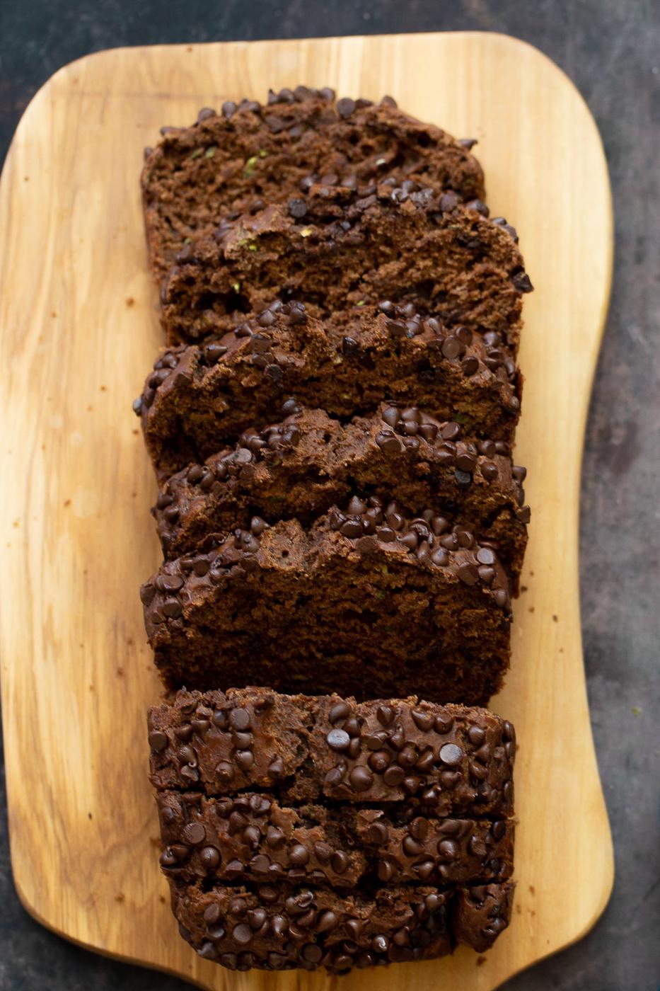 overhead shot of a sliced loaf of vegan chocolate zucchini bread on a wooden chopping board