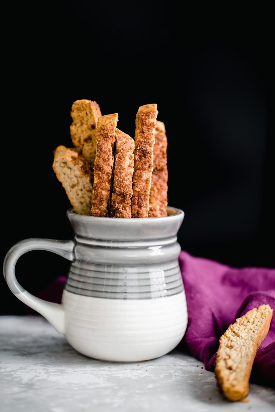 homemade vegan churro biscotti peaking out of a grey and white coffee mug
