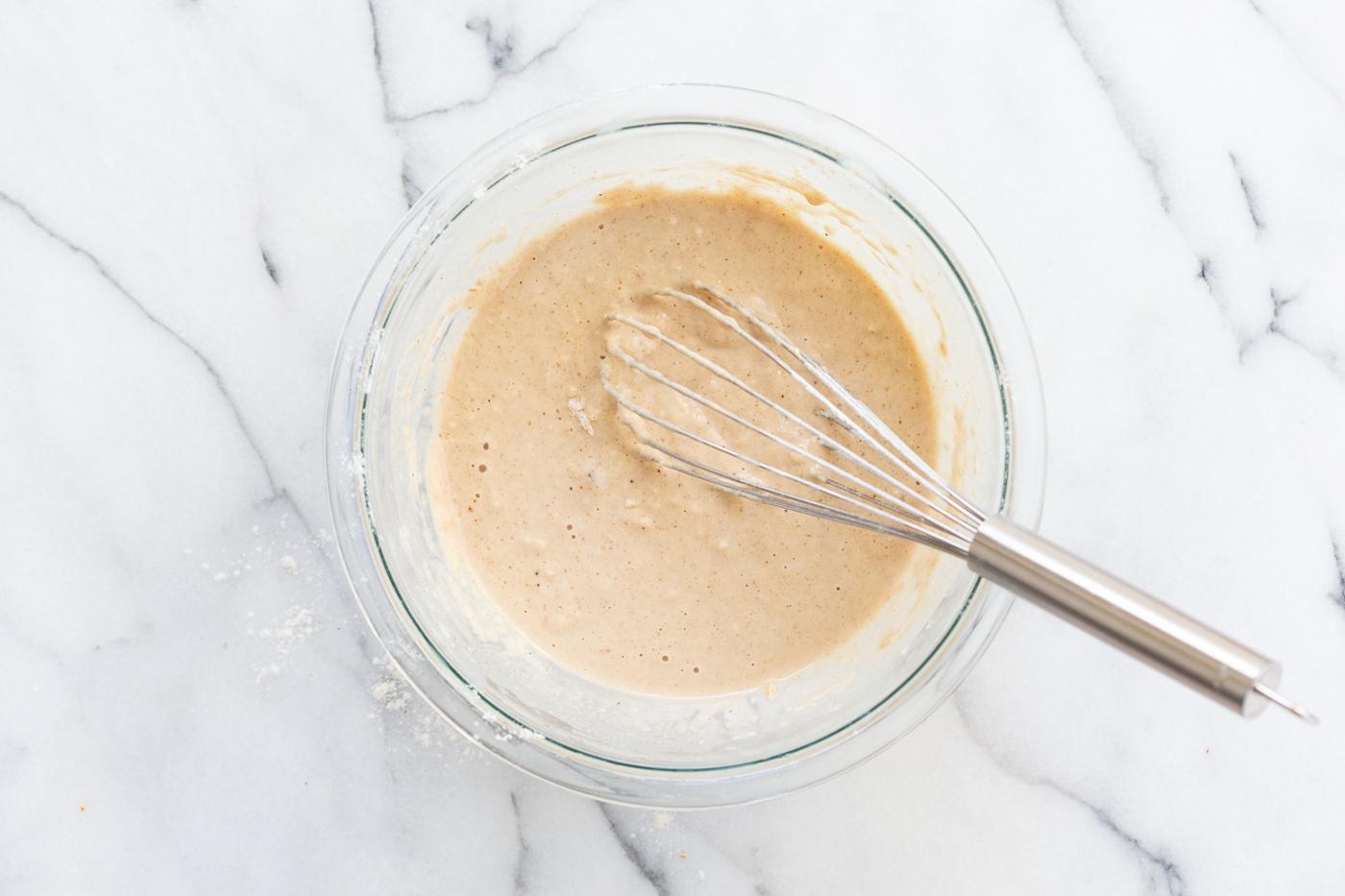 Vegan Cinnamon Streusel Pancakes batter in a glass bowl on Marble