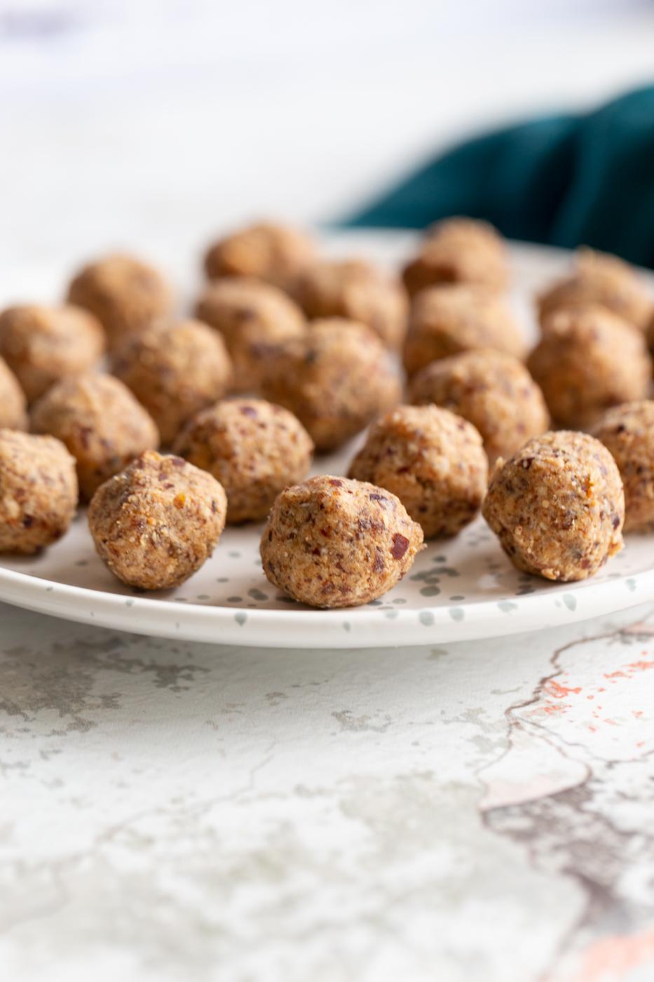 side view of a plate with vegan coconut caramel date energy balls