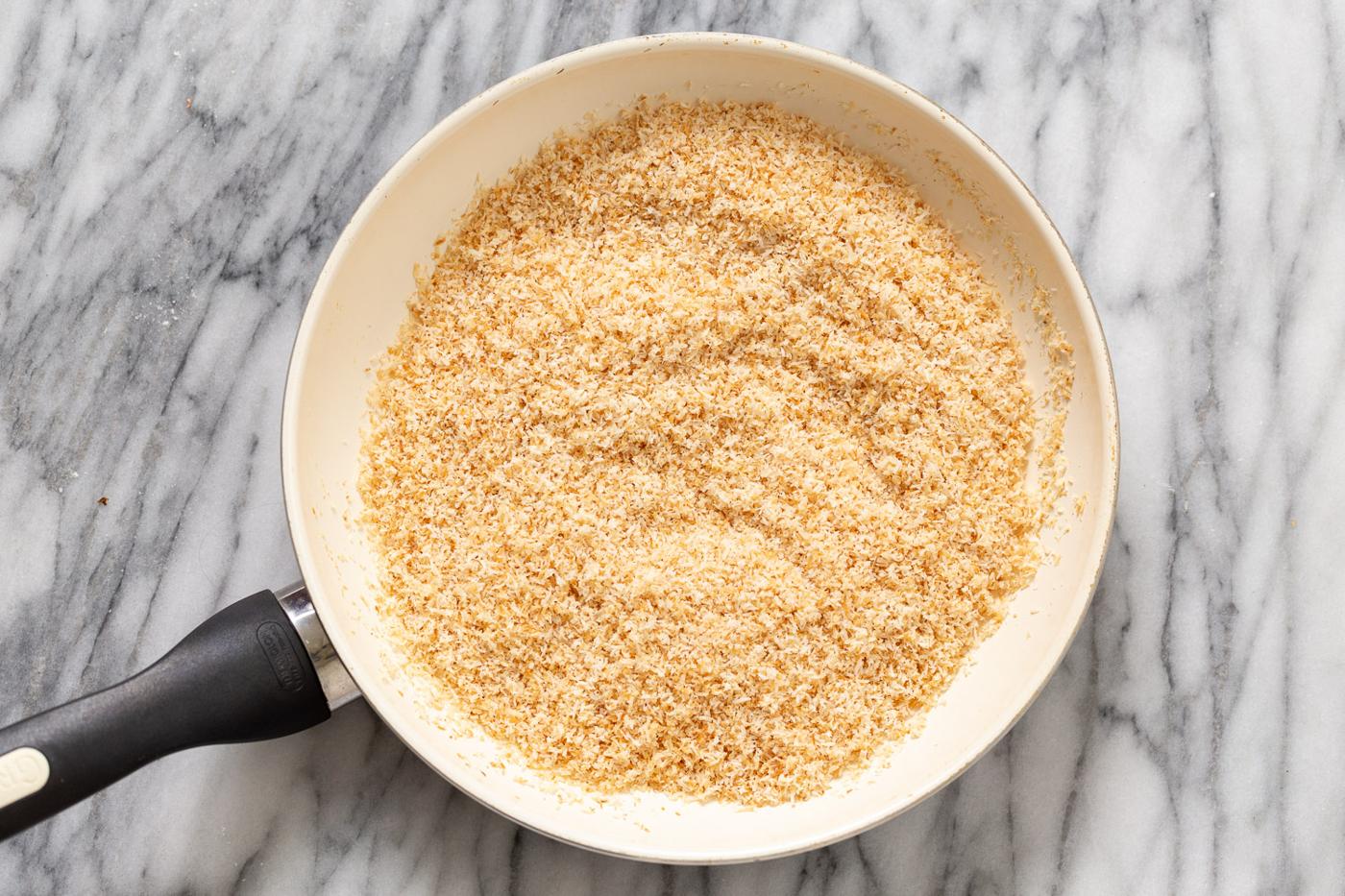 unsweetened coconut being toasted in a pan