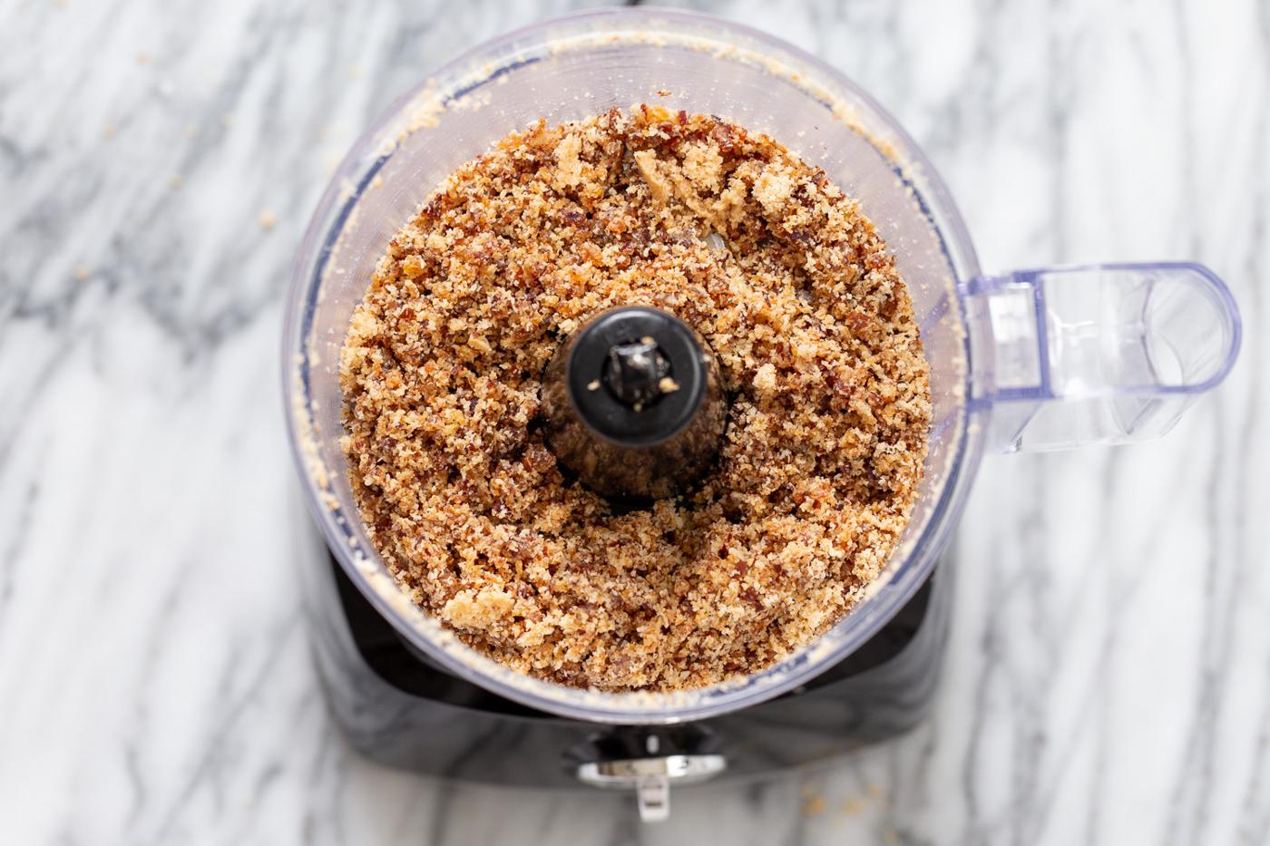 shredded coconut and dates in the container of a food processor