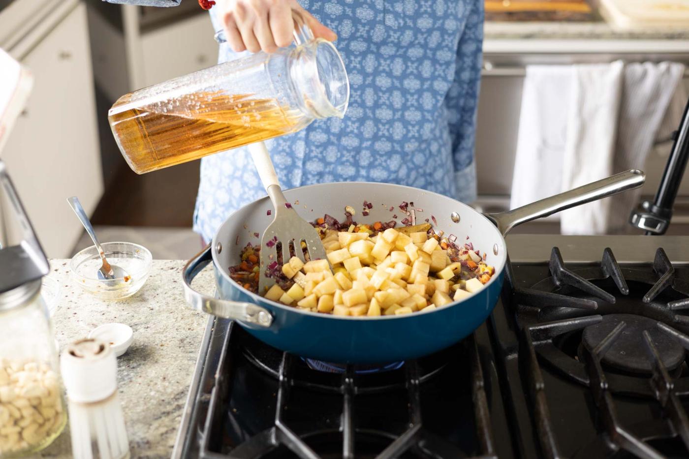 adding potatoes and stock to the pan