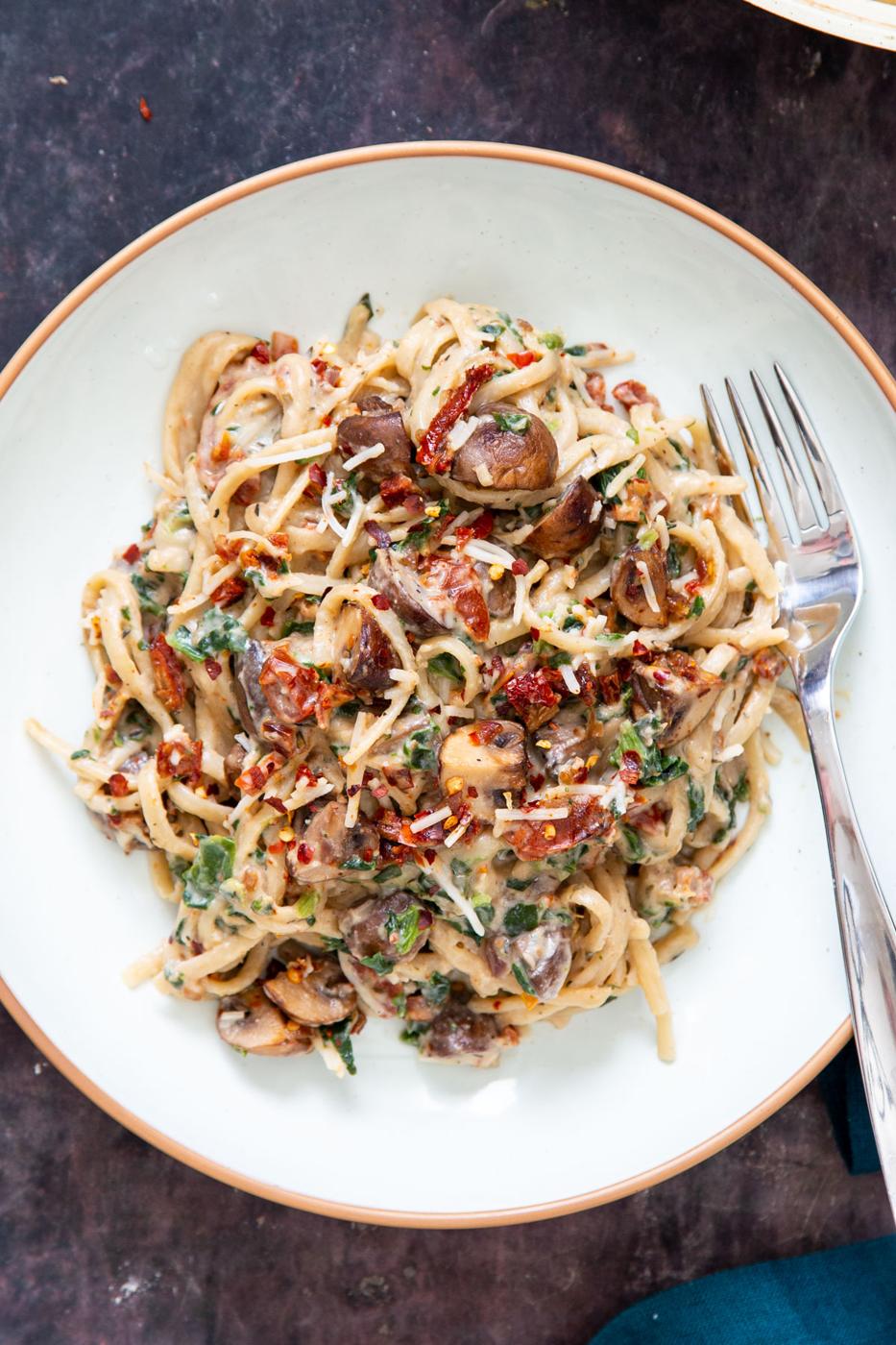 a plate with creamy vegan one pot mushroom pasta with spinach and sun-dried tomatoes