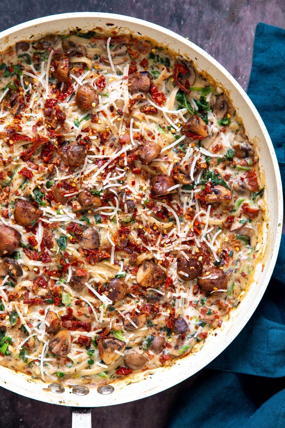 overhead shot of a saucepan with creamy vegan mushroom pasta with sundried tomatoes and spinach