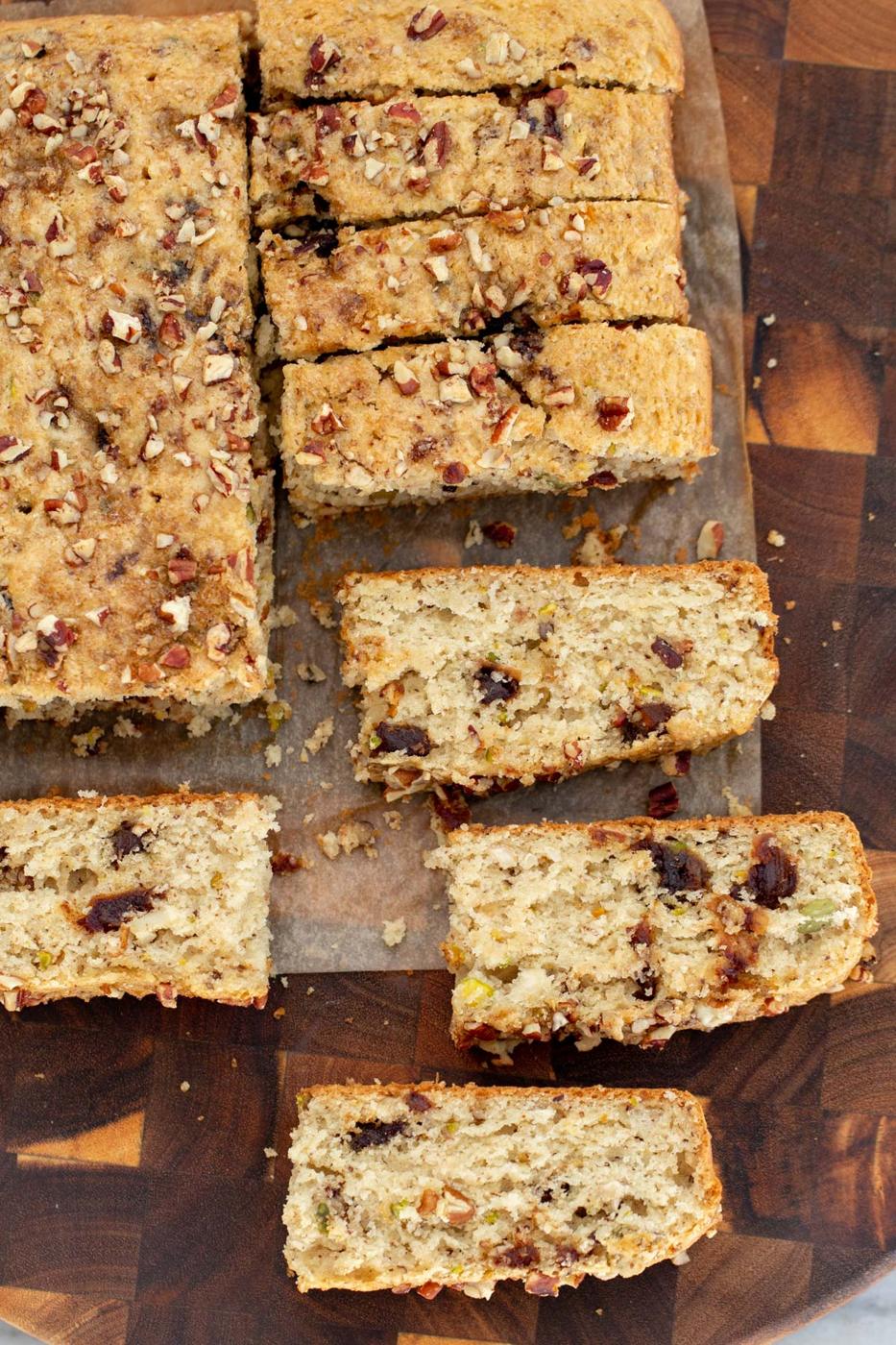 vegan date nut cake being cut into slices on a wooden board