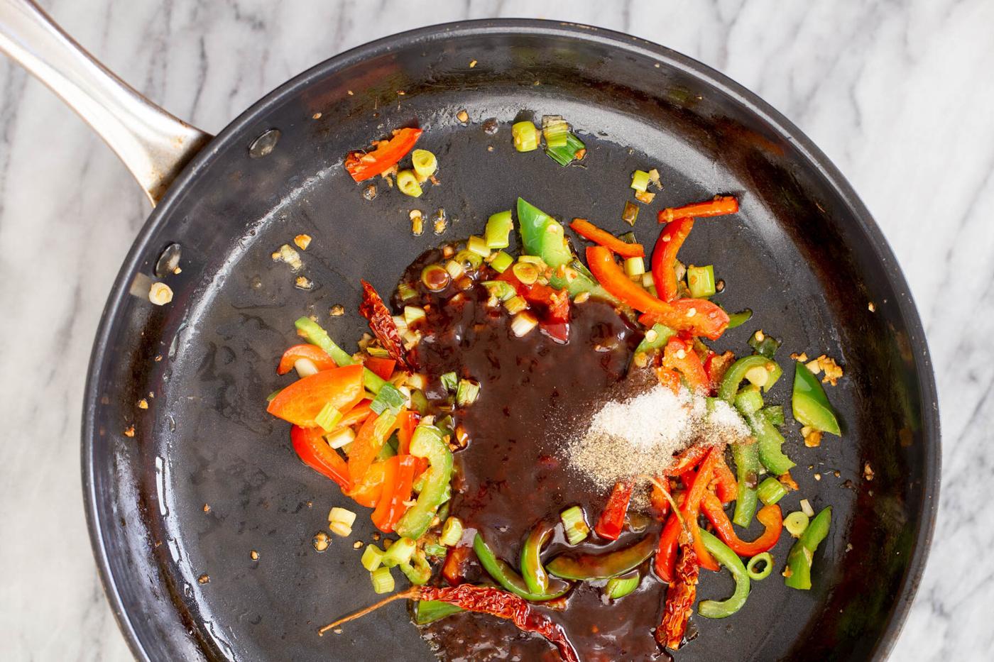 soy sauce and sambal olek being added to a frying pan