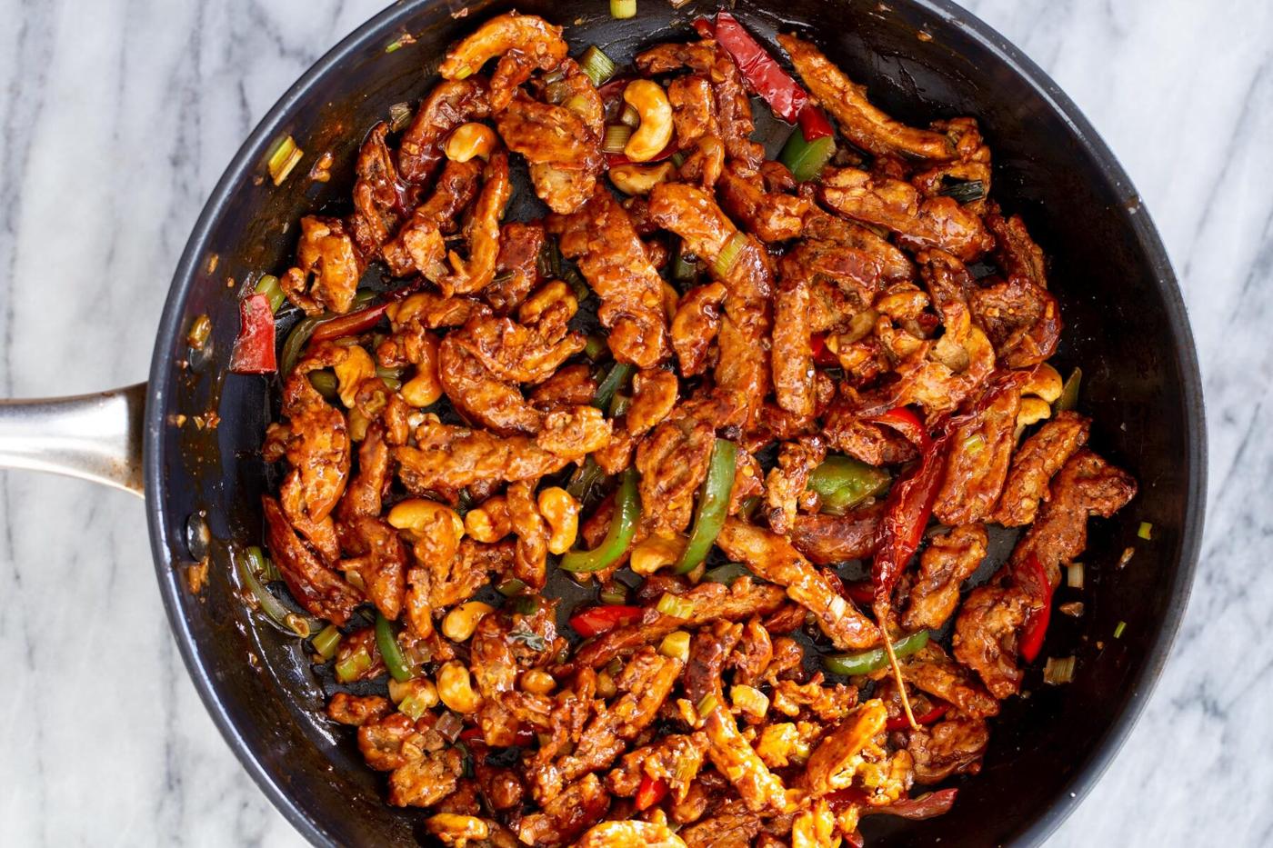 soycurls, cashews and bell peppers mixed with sweet and spicy sauce in a frying pan