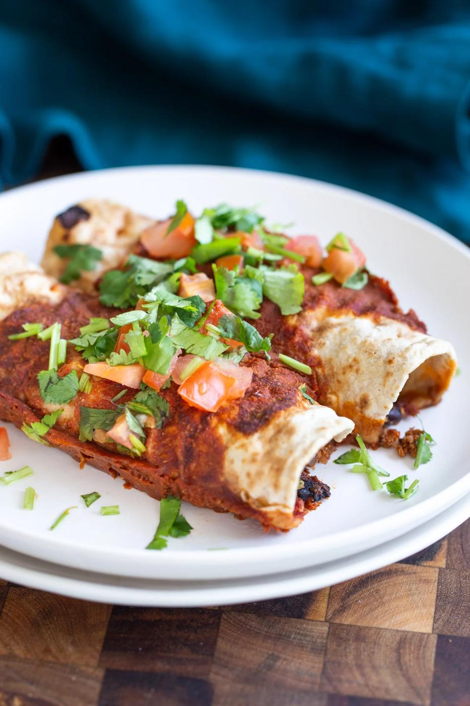 vegan enchiladas filled with cauliflower taco meat on white plates
