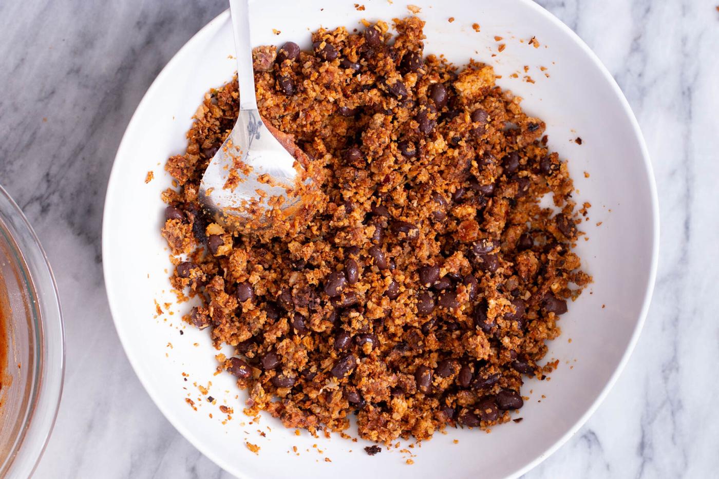a small dish with cauliflower taco meat being mixed with kidney beans