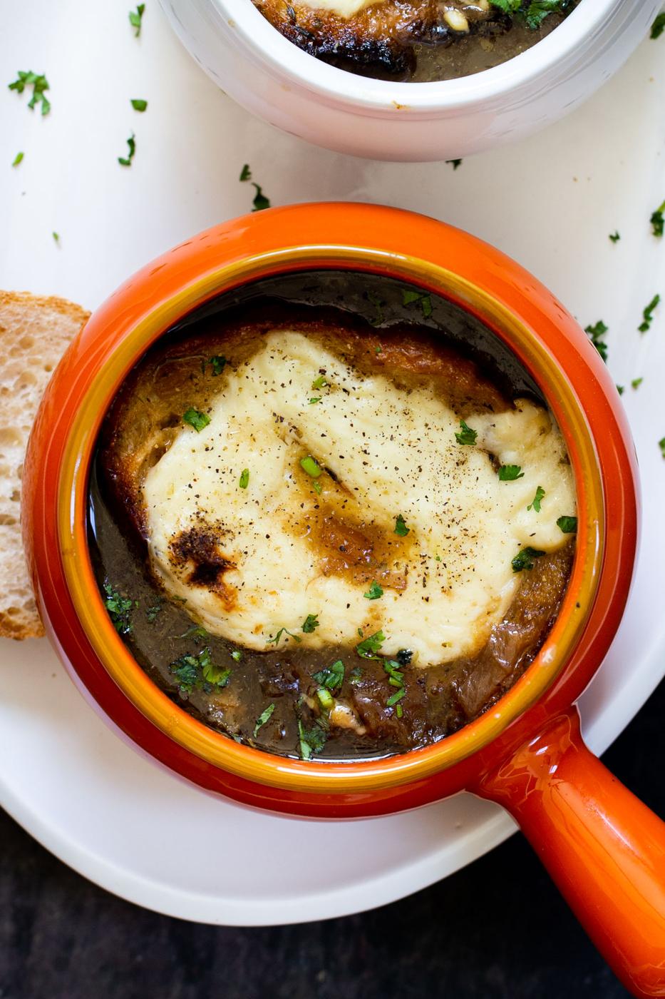 close up overhead shot of a small orange soup bowl with vegan French Onion Soup