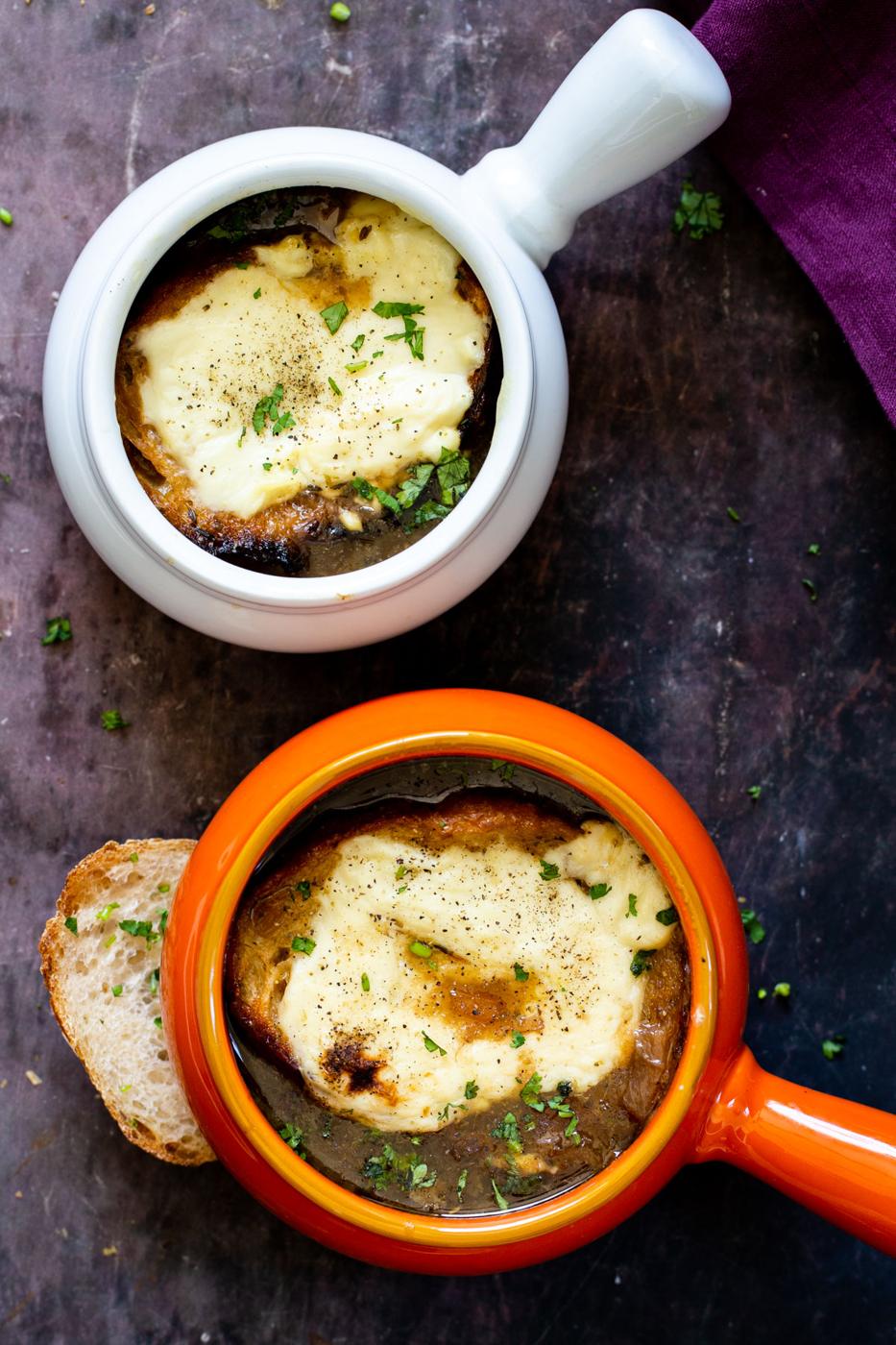 two Individual pots with vegan French Onion Soup topped with cheesy bread