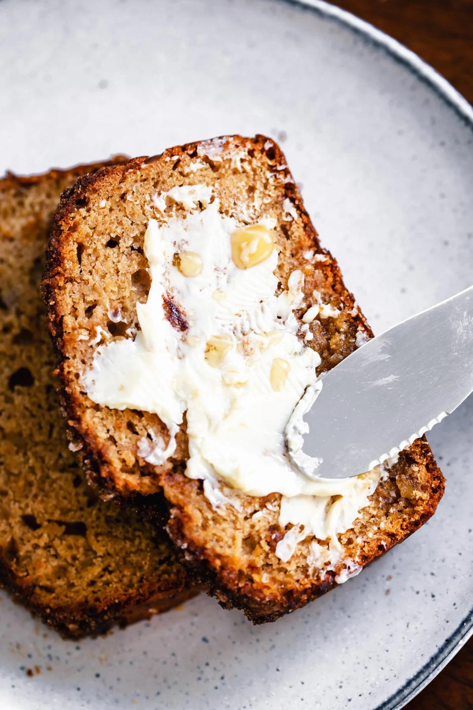 a slice of vegan gingerbread banana bread being buttered