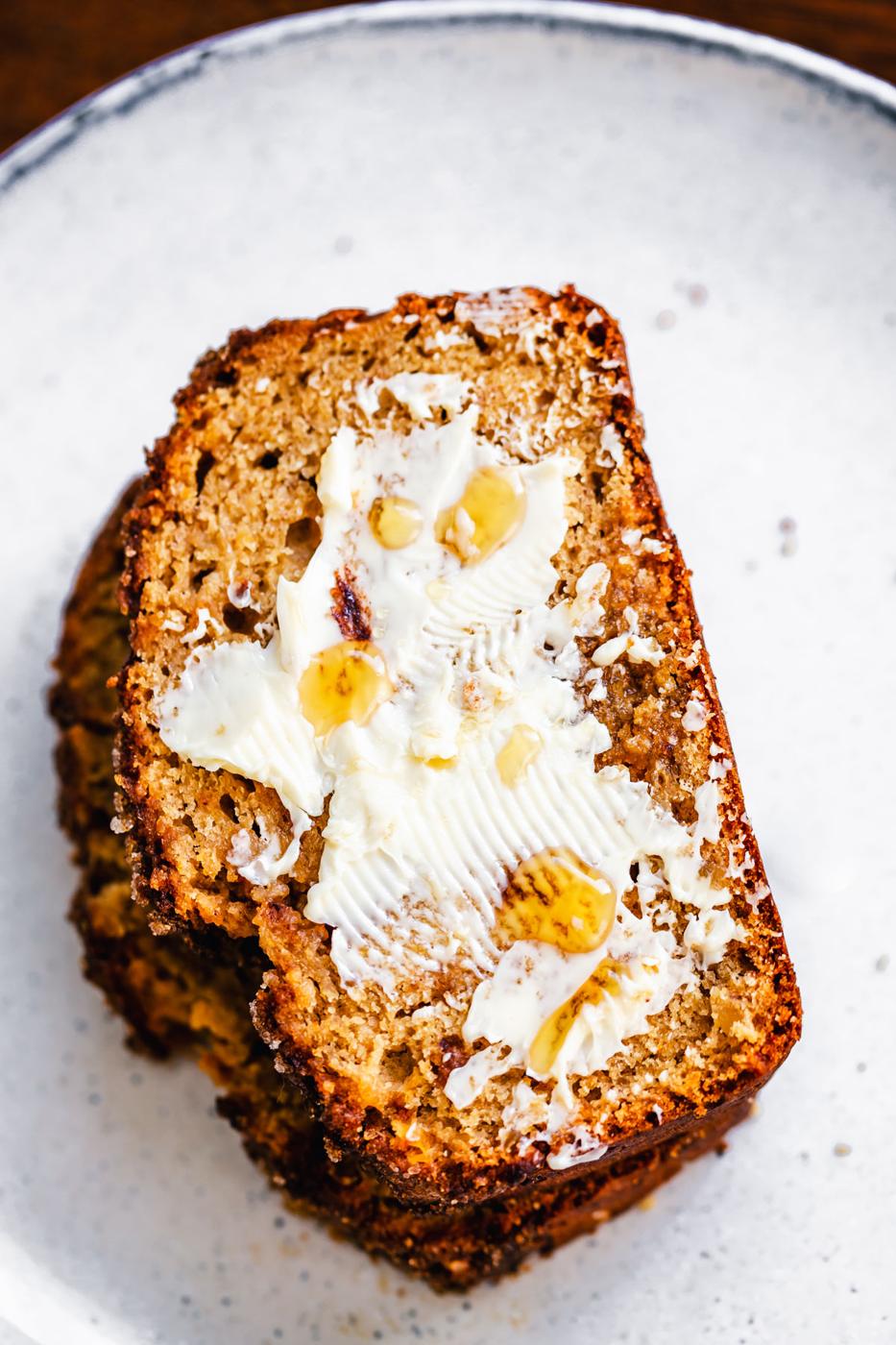 a slice of buttered banana gingerbread on a white plate